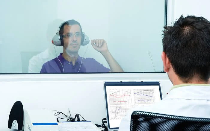 Audiologist reviewing a hearing test with a client in a sound booth